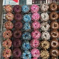 A tray of mini sprinkle donuts in chocolate, pink, blue and white.